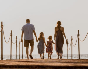 Couple walking with children near ocean
