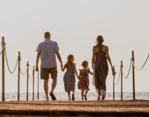 Couple walking with children near ocean