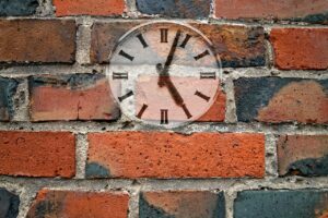 Red brick wall with clock at about 5:04 pm