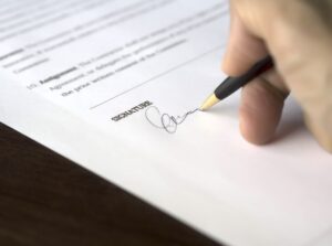 Persons hand signing their signature on a probate court bond application agreement
